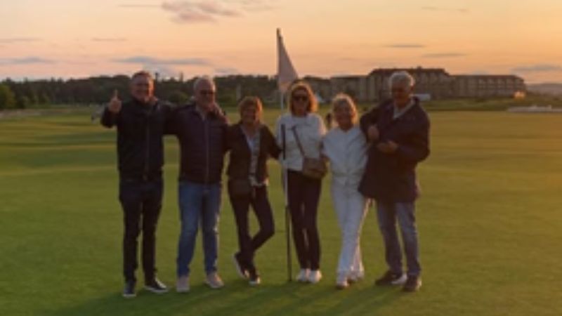 Sex personer står tillsammans på en golfbana i Edinburgh i kvällsljus.