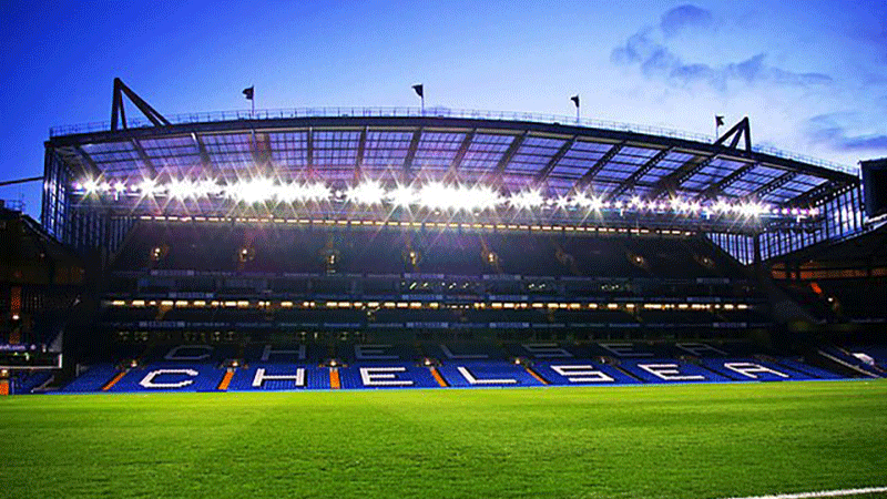 Upplyst läktare nattid på Stamford Bridge, London. Tar dig till fotbollsresor och biljetter Chelsea, Premier League, England. 